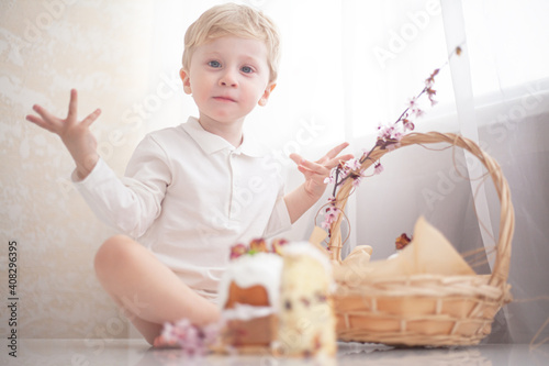 The kid eating traditional russian easter cake on table. The decorarion of kulich are the flower are cooking for spring holiday photo