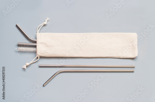 Fotografie Reusable stainless steel straws and cleaning brush with cream cotton bag on grey background