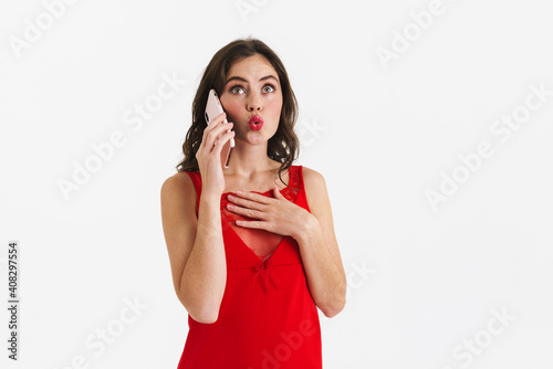 Surprised beautiful girl wearing red dress talking on mobile phone