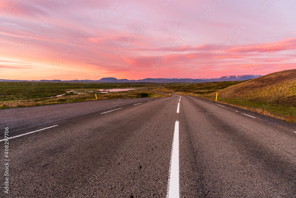 Majestic summer sunset over a winding mountain road leading down to a valley. Myvatn, Iceland.