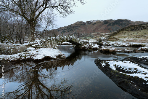 Slaters Bridge in Little Langdale on a cold Winters morning with snow on rocks. Lake District, UK. photo