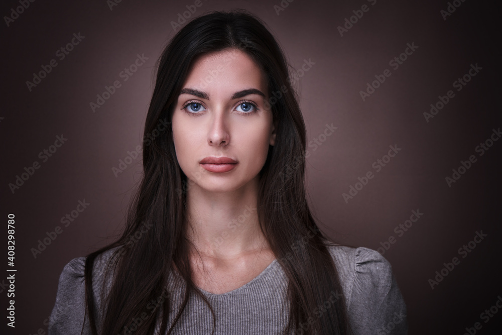 Portrait of beautiful brunette woman with serious face expression isolated in brown studio background Portrait of beautiful brunette woman with serious face expression isolated in brown studio background