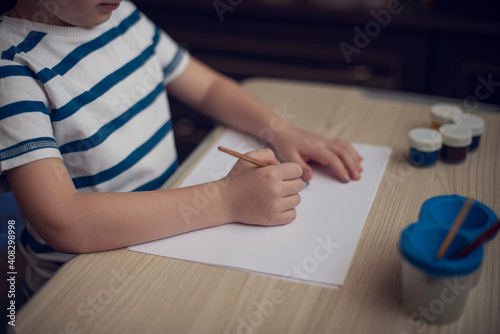Small boy draws at the table. Top view