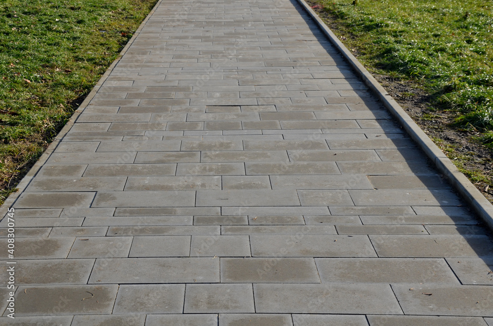 brown, gray concrete park path, curb on one side. tiles of different ...