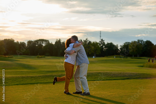 Mature loving couple hugging on the field. Man and woman embracing each other outdoors side view.