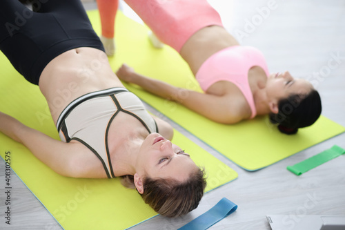 Two women on rugs do exercises for buttocks