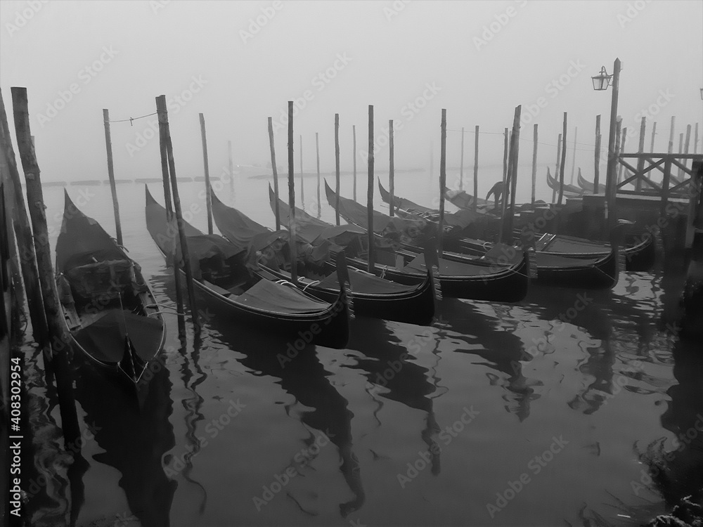 Venice, Italy, January 27, 2020 evocative black and white image of gondolas moored along a pier
