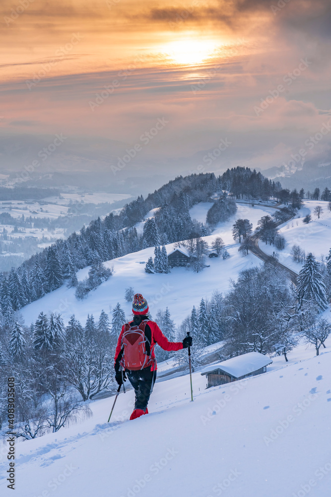 nice active senior woman snowshoeing in the Allgaeu Alps near Oberstaufen with view into the Bregenzerwald, Vorarlberg, 