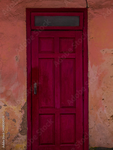 Vintage red wooden door. Antique building exterior detail. Street photo. Retro wood boards. Empty abstract grunge burgundy painted texture, colorful weathered wall. © KawaiiS