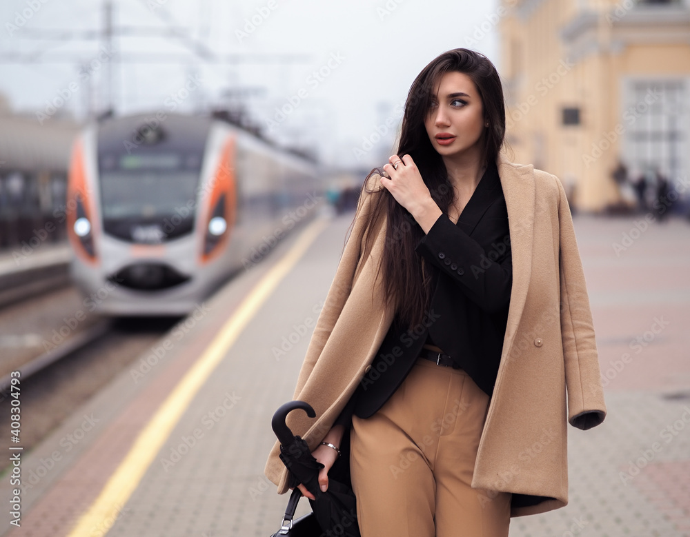 Fototapeta premium Woman model stands at train station in suit