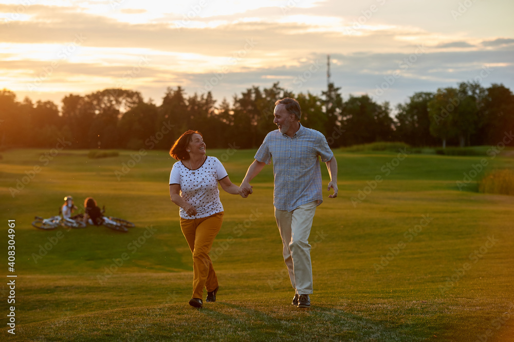 Happy smiling couple holding hands and running. Green field background. Happy smiling couple holding hands and running. Green field background.