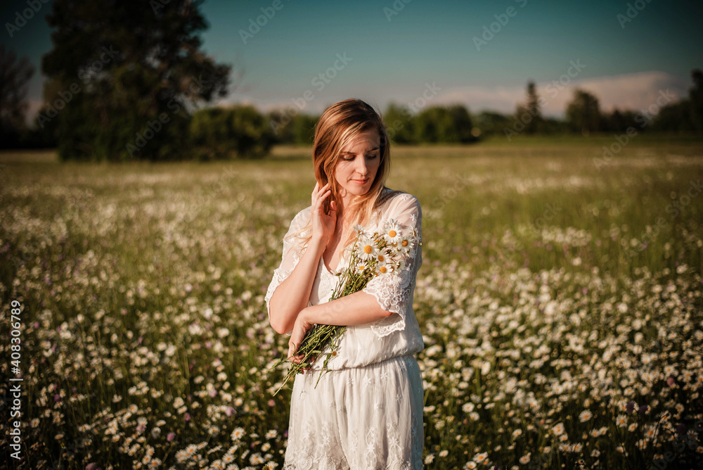 Young fashionable woman holding bunch of daisies in her hands wearing a lace playsuit in the middle of daisy meadow Young fashionable woman holding bunch of daisies in her hands wearing a lace playsuit in the middle of daisy meadow