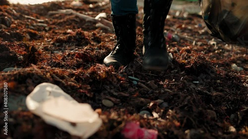 Wallpaper Mural Concept of world day Earth. A volunteer walks along a dirty beach, in rubber gloves, picks up garbage and puts it in a plastic bag. Slow motion. Torontodigital.ca