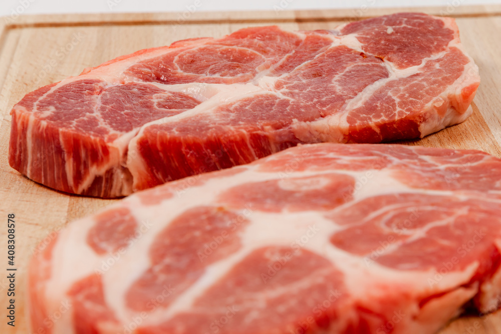 fresh raw marbled pork steak on a solid beech wood cutting board fresh raw marbled pork steak on a solid beech wood cutting board