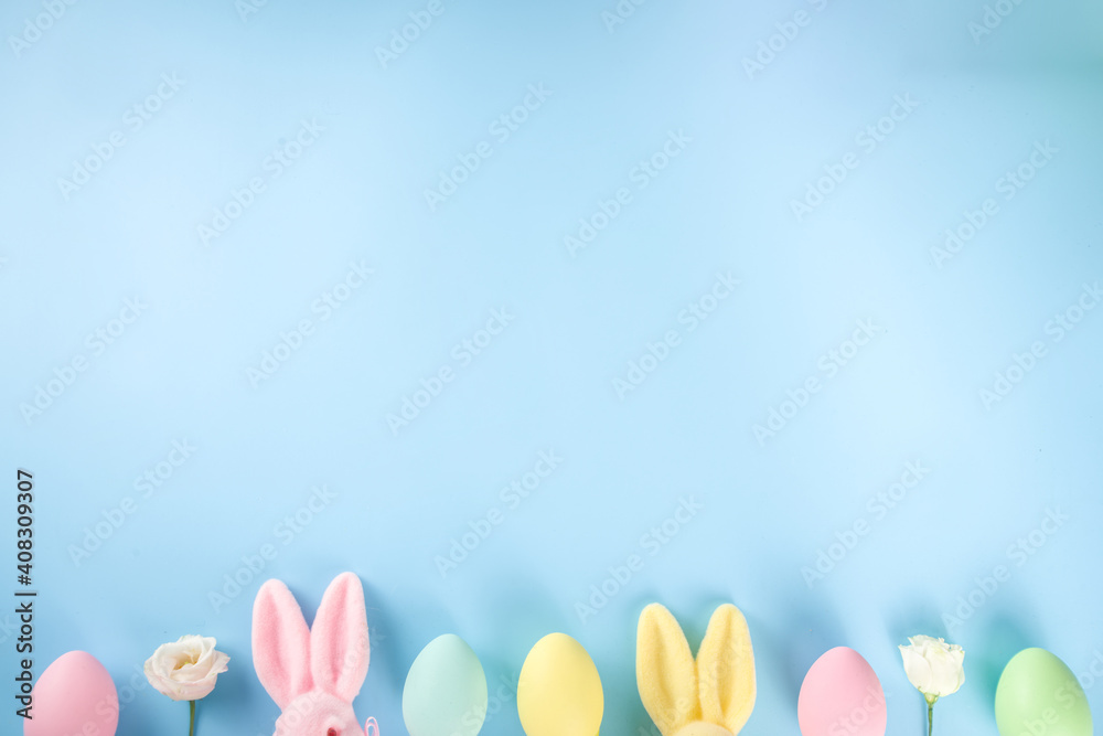 Spring Easter holiday greeting card, sale, invitation background. Colorful Easter Eggs and Bunny Rabbits, with Spring flowers on blue background top view flatlay with copy space for text