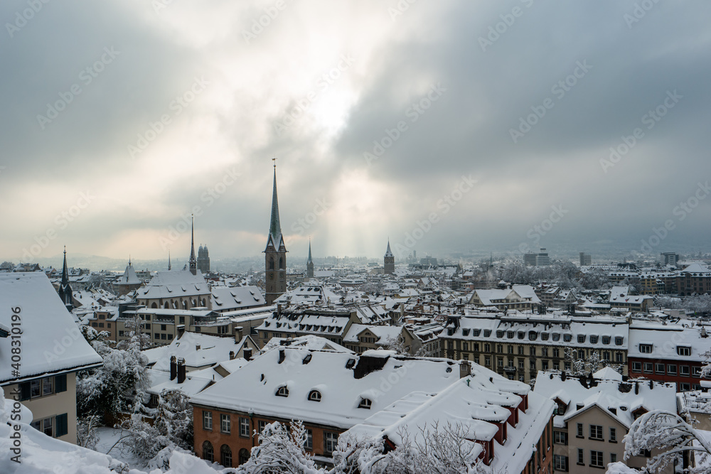 Snow covered old town Zurich with church bell tower winter time cloudy day