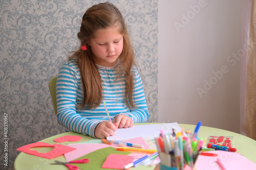 A child girl draws, paints, cuts out a heart. Children's creativity. gift for valentine's day, mother's day, father's day. Classes during the lockdown quarantine at home 