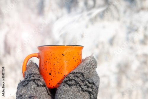 mug in hands in mittens on a snowy background in winter