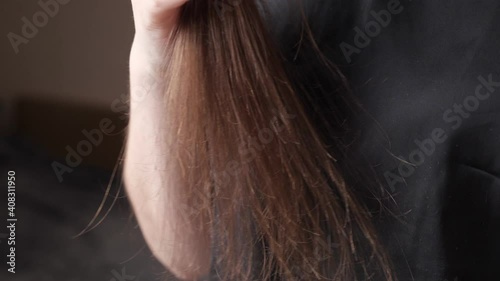 Skilled woman hands comb split and overdried long dark brown hair tips gently holding special black brush extreme close view slow motion photo