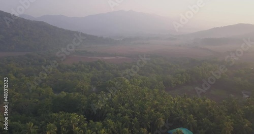 Stunning Misty Mountain Ranges With Densely Forest Of Palm Trees At Palolem Beach, Canacona, South Goa, India. - Aerial Pullback Shot photo