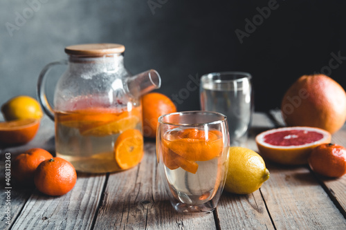 Citrus tea in a transparent teapot on a table with grapefruit and on a wooden table. Healthy drink.