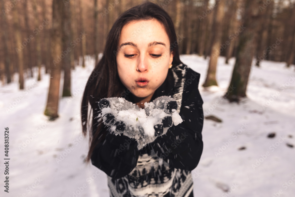Young woman blowing snow on her hands Young woman blowing snow on her hands