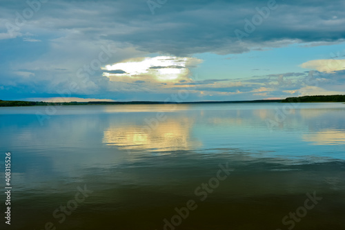 A calm evening sky landscape of pastel colors with a reflection in the smooth waves of a large lake. Natural background