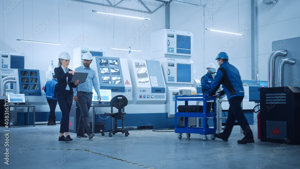 Female Chief Engineer and Male Project Manager Walk Through Modern Factory, Talking and Planning Optimization of the Production. Industrial Facility: Professionals Working on CNC Machinery, Robot arm
