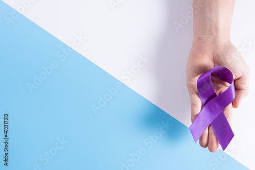 World cancer day, hands holding purple ribbon on with and blue background with copy space for text. Healthcare and medical concept.