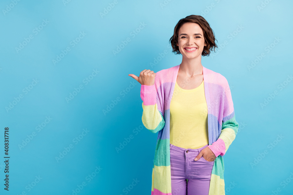 Photo portrait of girl pointing thumb at blank space isolated on pastel blue colored background Photo portrait of girl pointing thumb at blank space isolated on pastel blue colored background