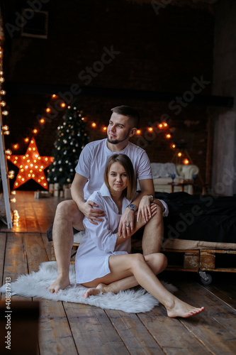 couple dressed in white against the background of christmas lights