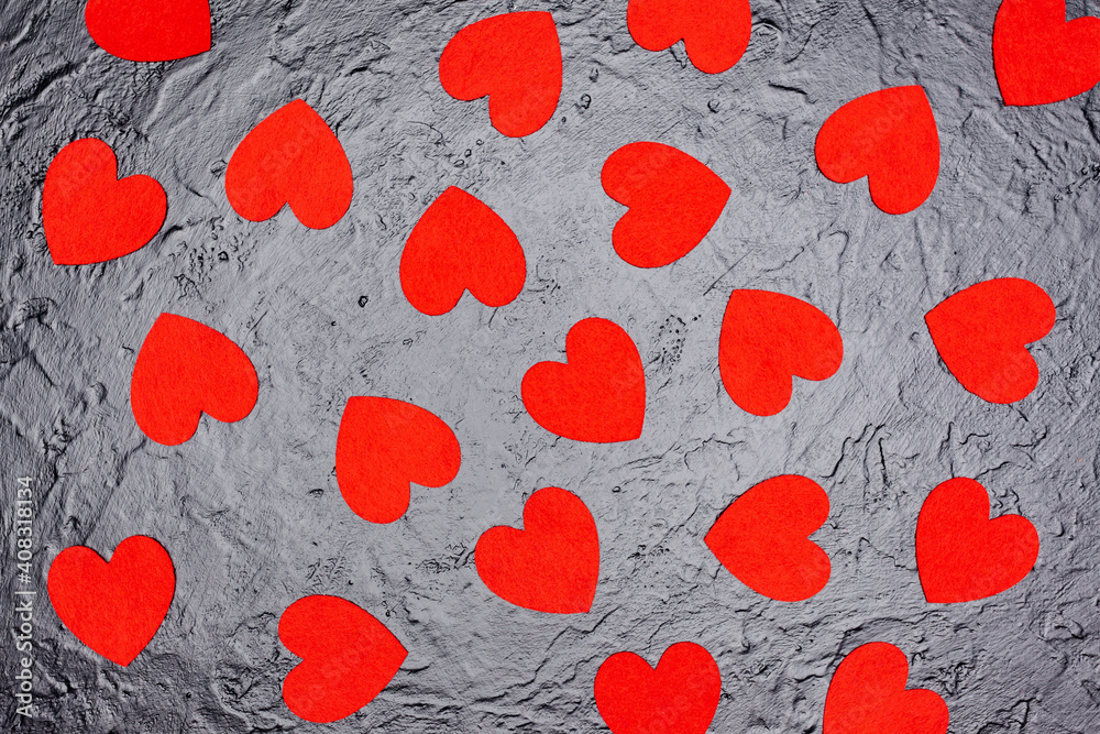 on a black factor background lies many red hearts, used as a background or texture, view from above on a black factor background lies many red hearts, used as a background or texture, view from above