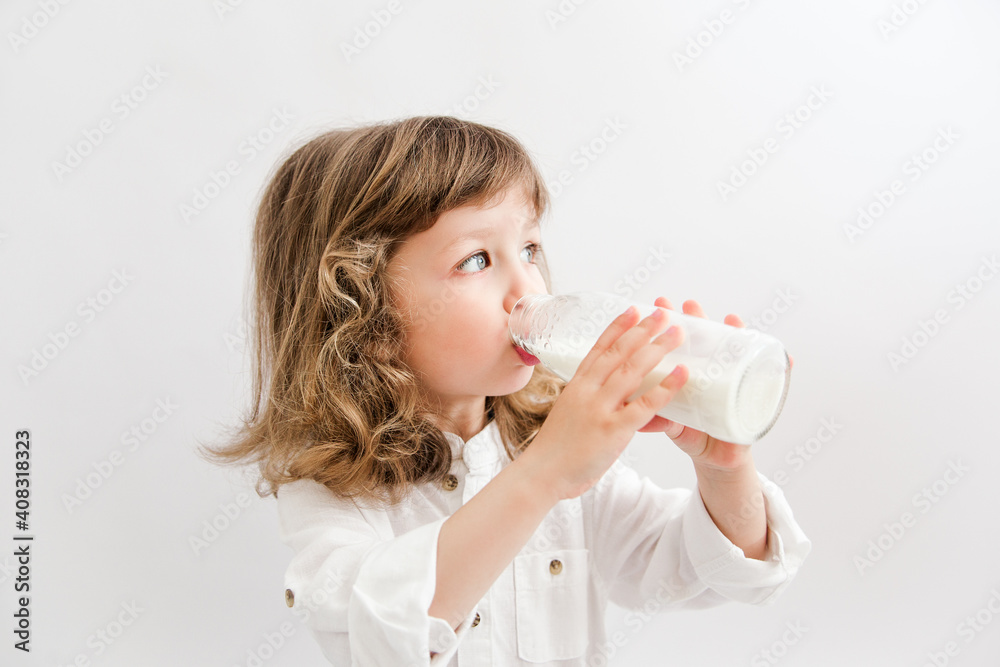 beautiful girl with curly hair and blue eyes drinks milk from a bottle. white background. beautiful girl with curly hair and blue eyes drinks milk from a bottle. white background.