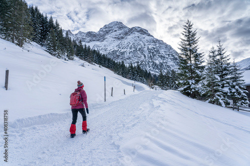 active senior woman hiking in the snowy mountains of Kleinwalsertal, Vorarlberg, Austria, near village of Baad, below the summit of Widderstein 