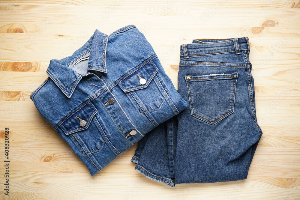 Jeans women's jacket and denim pants on the wooden background, flat lay.