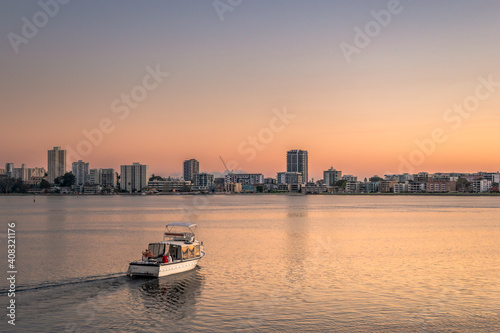 People on boat in river infront of city during sunset © Frederic