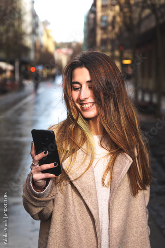 Young caucasian brunette woman using a smartphone at the street