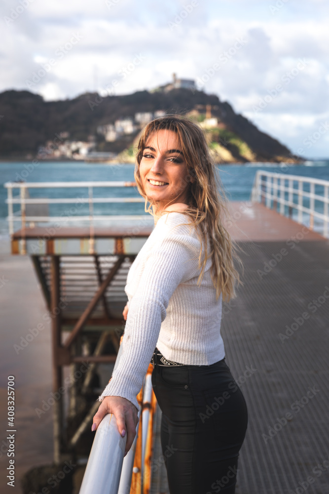 Young caucasian blonde woman at the pier of Donostia-San Sebastian; Basque Country.