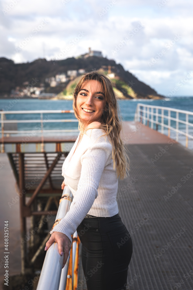 Young caucasian blonde woman at the pier of Donostia-San Sebastian; Basque Country.