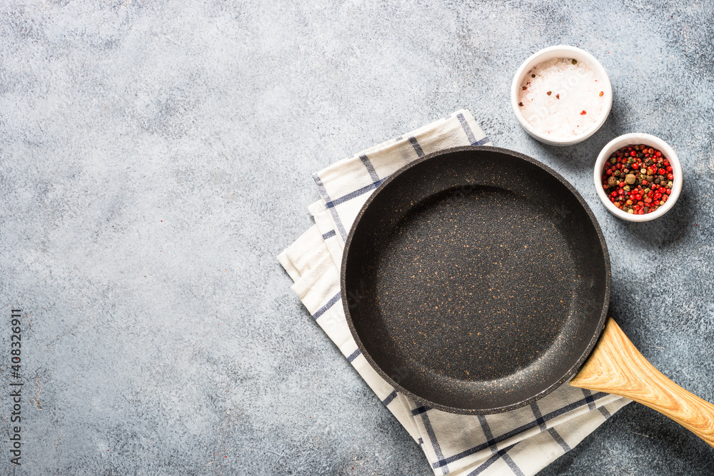 Fototapeta premium Frying pan or skillet with stone nonstick coating on light stone table. Top view with copy space.