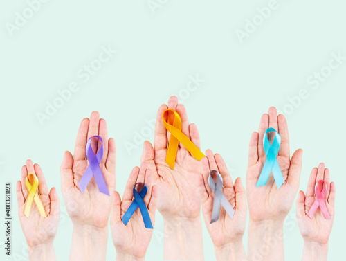 Hands hold multicolored ribbons, symbol of the fight against cancer. World cancer day photo