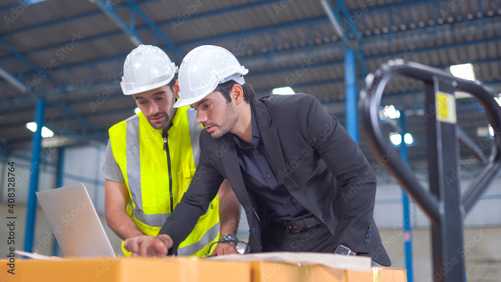 Warehouse worker and manager checking product in a large warehouse Warehouse worker and manager checking product in a large warehouse