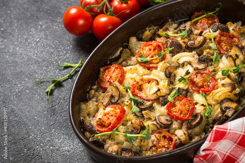 Baked meat with vegetables. Pork, onion, tomato and mushrooms baked in the oven. Top view image with space for text.