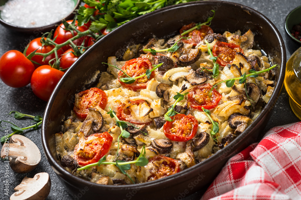 Baked meat with vegetables. Pork, onion, tomato and mushrooms baked in the oven.