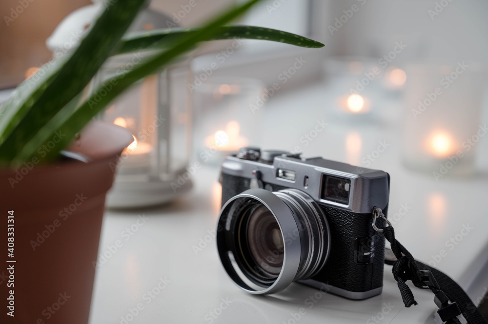 Close-up of vintage camera on white sill. Old fashion. Retro hipster photography. Burning candles on background. Hygge concept.