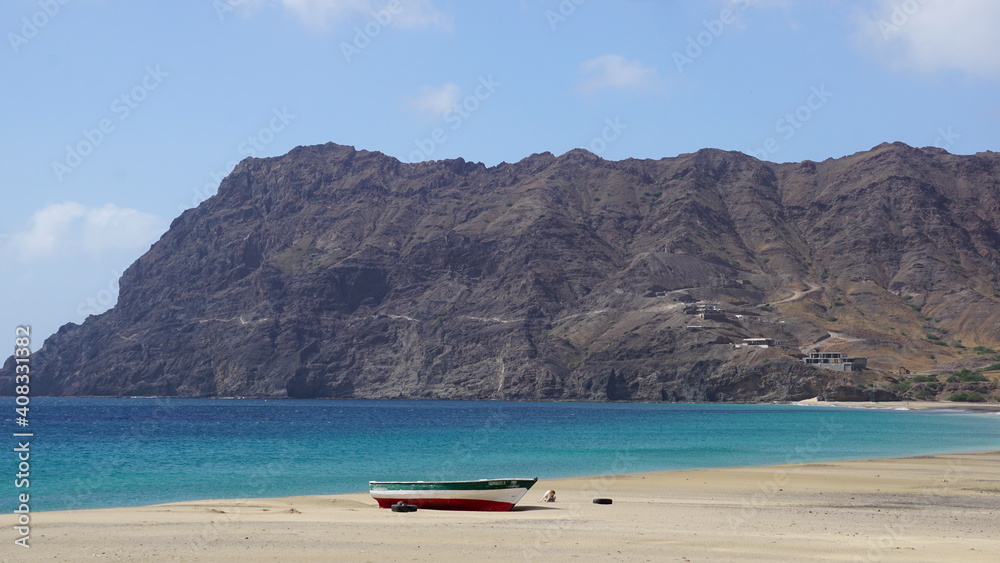 a boat on the beach of Sao Pedro with the view of the light house Farol de Dona Amelia, on the island Sao Vicente, Cabo Verde, in the month of December