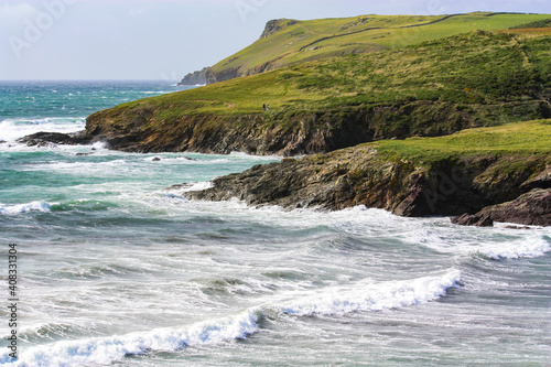 coastal seascape with green headland ,rocky outcrops , golden empty beaches with waves and surf sea.