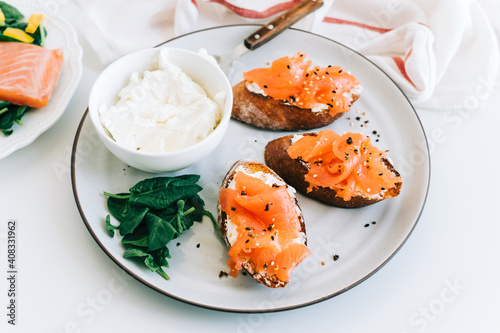Delicious toast with salmon and cheese cream on a white plate whit spinach.