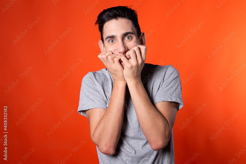 The young man is actively gesturing. Expression of emotions. Blue clothes. Orange background. Point of view. The young man is actively gesturing. Expression of emotions. Blue clothes. Orange background. Point of view.
