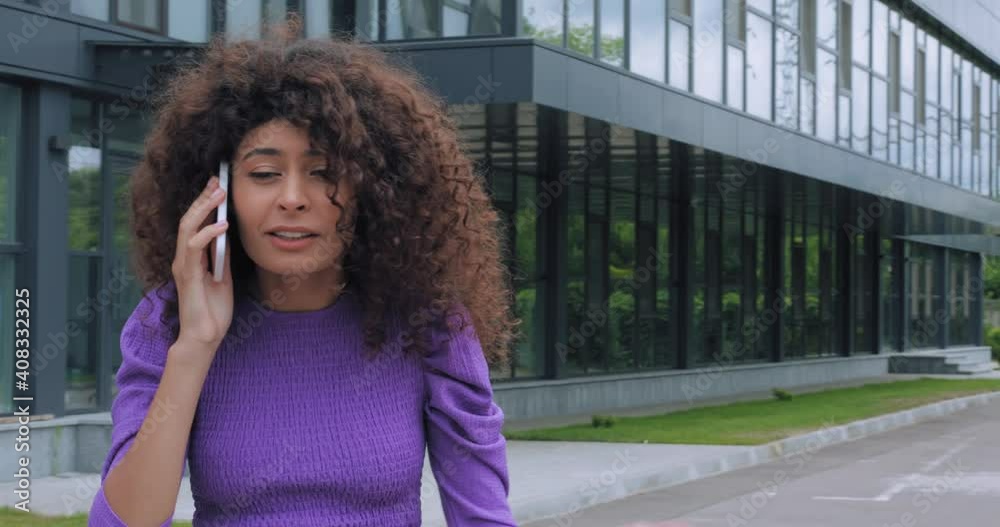 curly woman quarrelling while talking on smartphone outside curly woman quarrelling while talking on smartphone outside